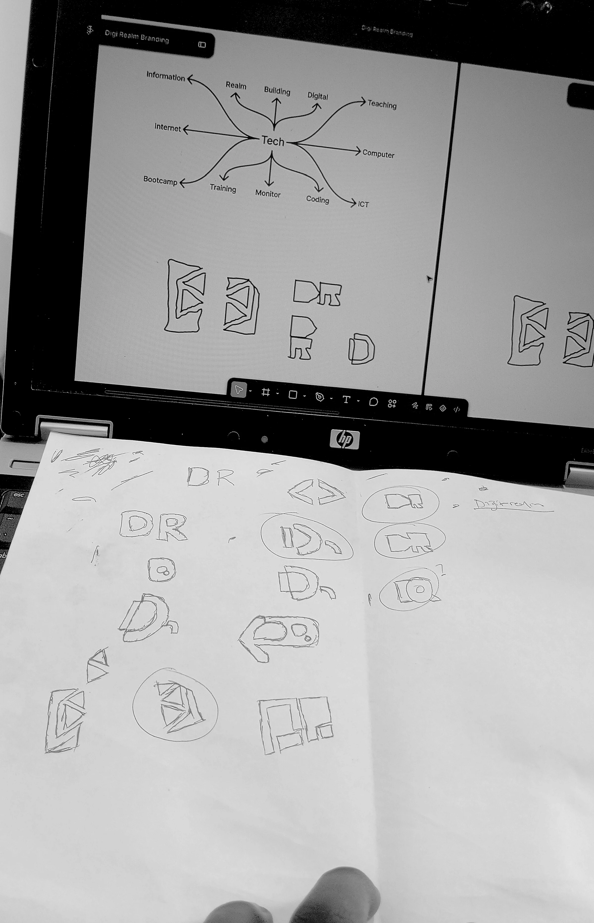 Paper sketches alongside digital logo exploration