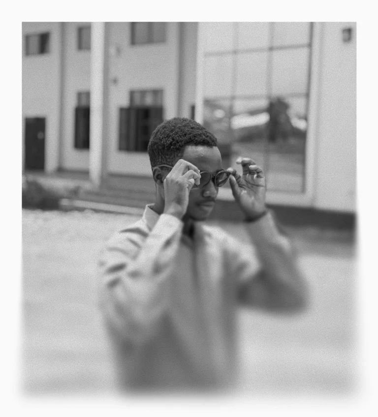 Black and white portrait of Just Joel adjusting his glasses